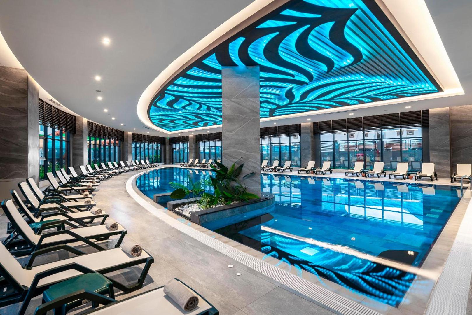 Kirman Calyptus Resort & SPA iekštelpu baseins ar māksliniecisku griestu apgaismojumu un ērtiem zviļņiem relaksācijai spa centrā.