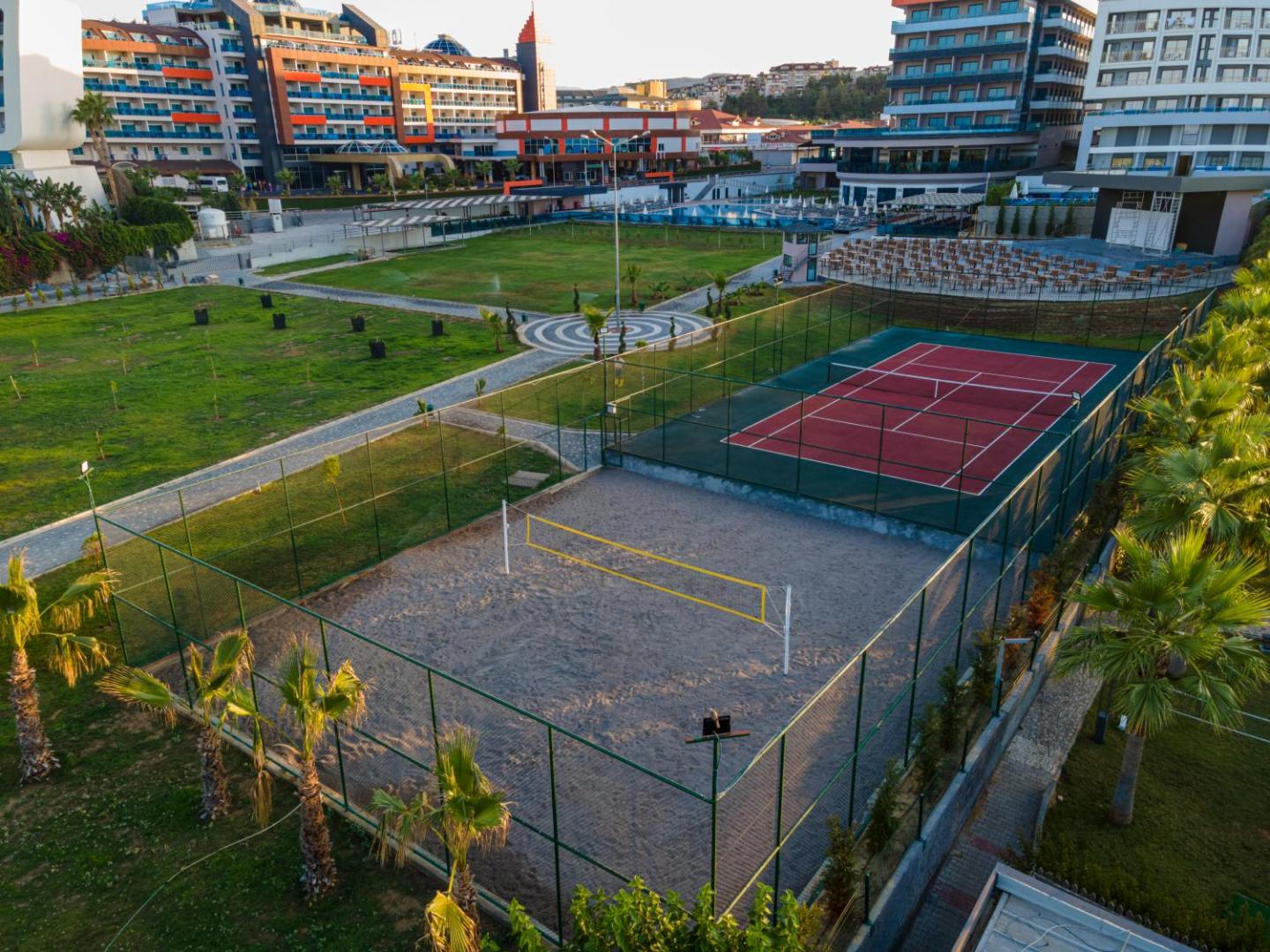 Lonicera Premium viesnīcas sporta laukumi no augšas — tenisa korts un pludmales volejbola laukums blakus zaļajai zonai