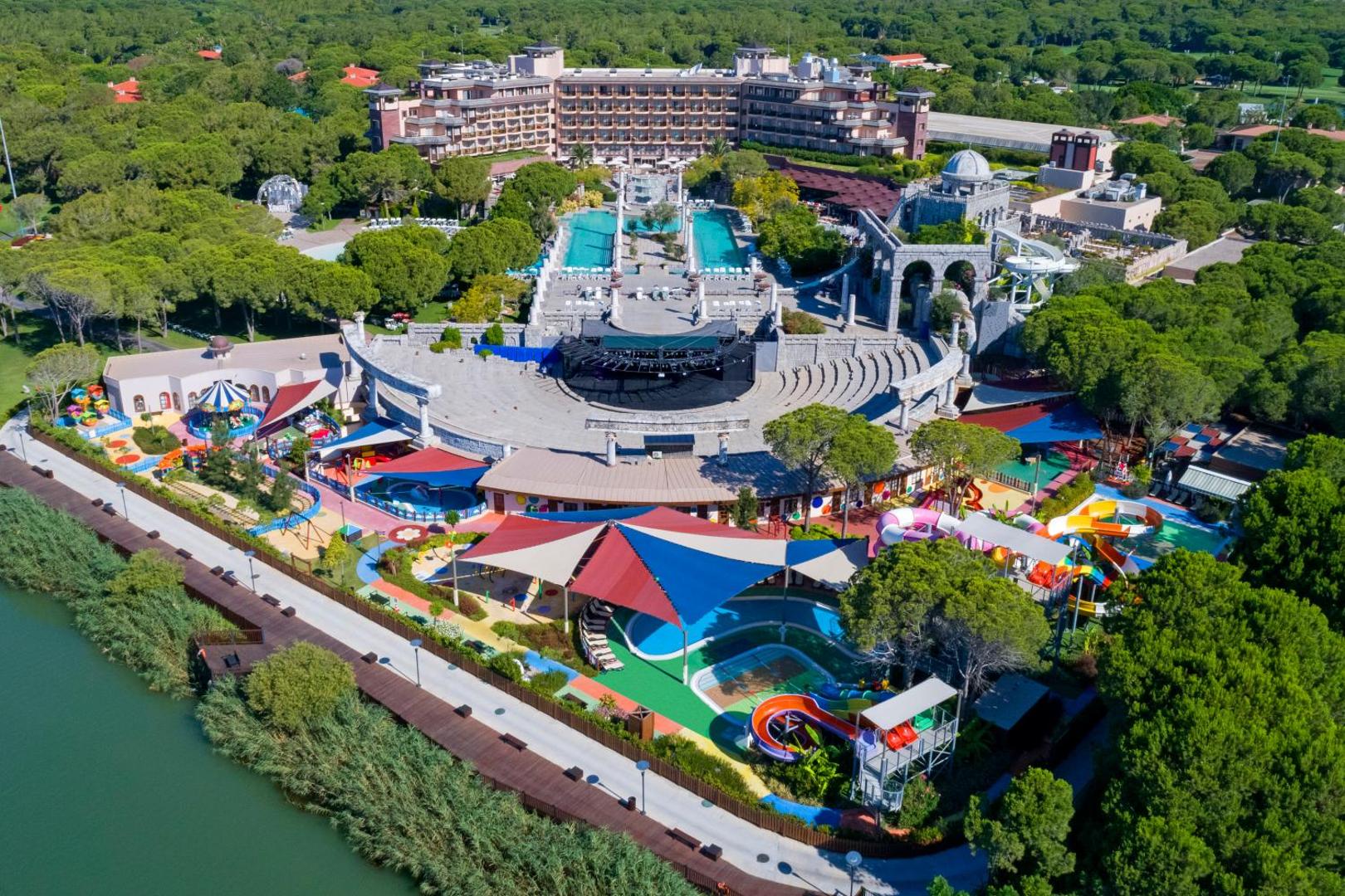 Xanadu Resort Hotel bērnu izklaides zona ar krāsainiem slidkalniņiem, rotaļu laukumiem un amfiteātri pie upes krasta Turcijā