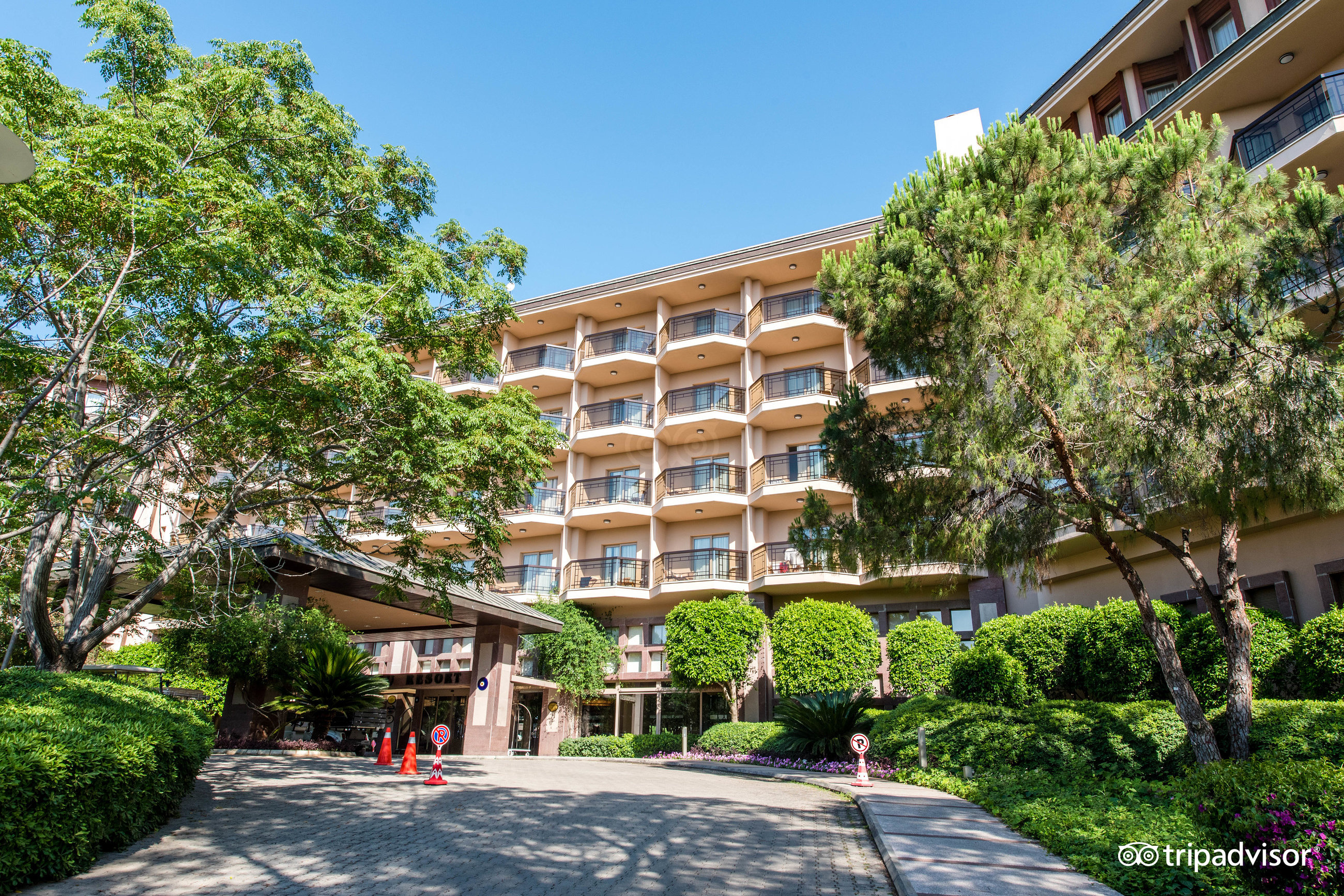 Xanadu Resort Hotel galvenā ieeja un fasāde ar balkoniem, ko ieskauj kupli koki un labiekārtota apstādījumu zona