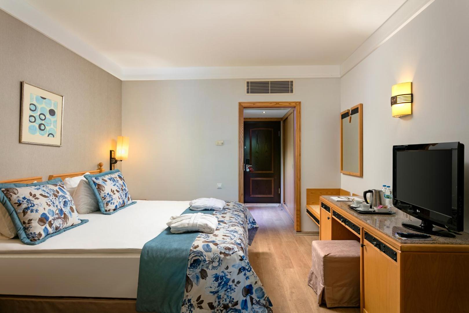 Xanadu Resort Hotel divvietīgs numurs Belekā ar ziedu raksta gultas veļu, koka mēbelēm, televizoru un tējas pagatavošanas komplektu