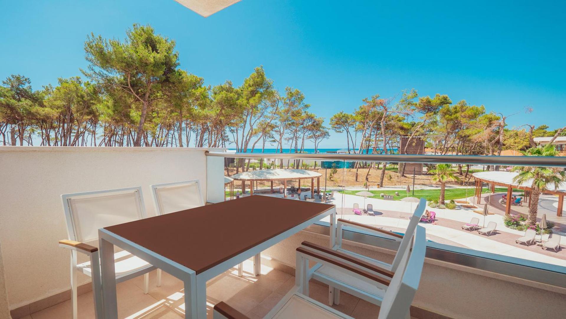 Azul Beach Resort Montenegro numura balkons ar galdu un krēsliem, skats uz priežu parku un Adrijas jūru Ulciņā.
