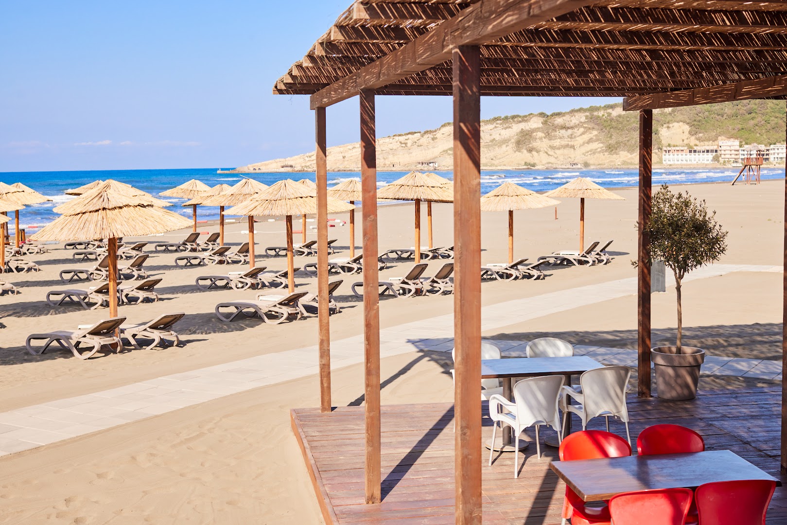 Azul Beach Resort Montenegro pludmales bāra terase ar galdiņiem un skatu uz saulessargiem piekrastē Ulciņas reģionā
