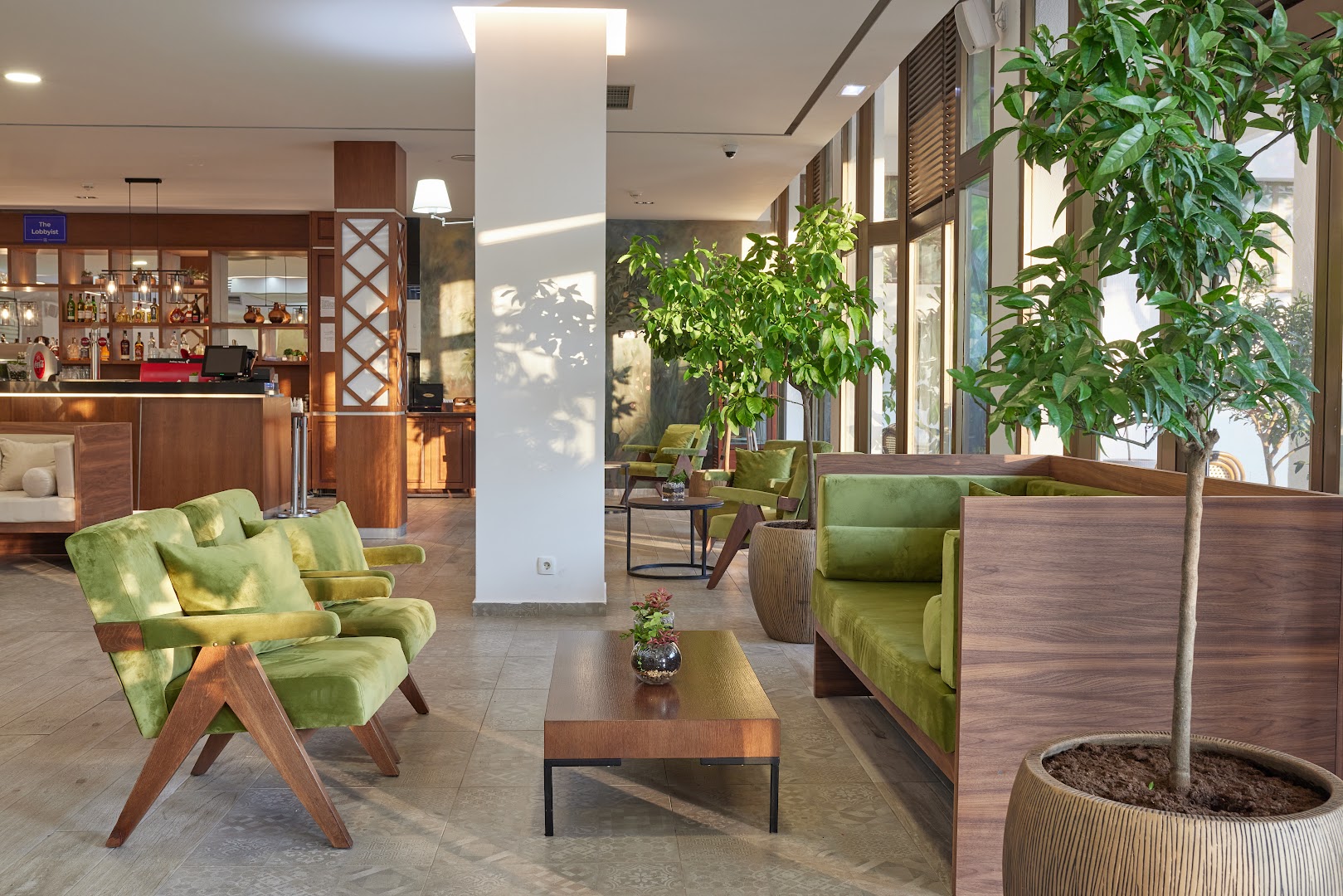 Azul Beach Resort Montenegro lobby atpūtas zona ar mīkstajiem krēsliem, koka galdiņiem un skatu uz bāra zonu