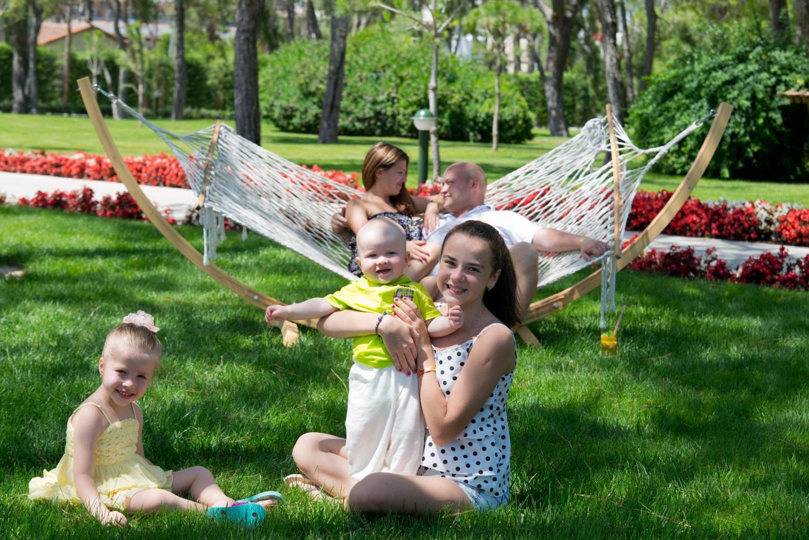 Ģimenes atpūta Marvida Family Eco dārzā ar šūpuļtīklu un plašu zālienu priežu meža ielokā