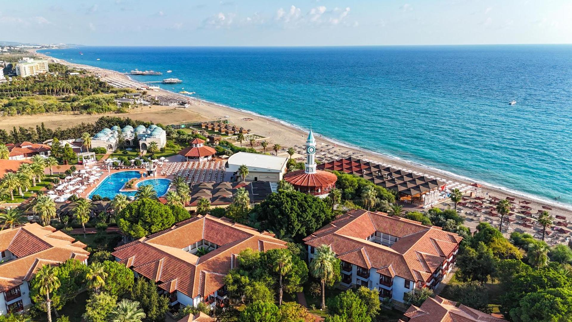 Ali Bey Club kūrorta panorāmas skats Side, Turcijā — plaša teritorija ar baseiniem, pludmali un Vidusjūras piekrasti saulainā dienā