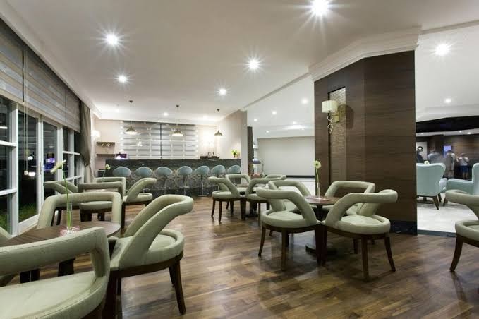Selectum Family Resort Belek lobby bārs ar modernām mēbelēm un koka apdari — mājīga atpūtas zona ar bāra leti un krēsliem