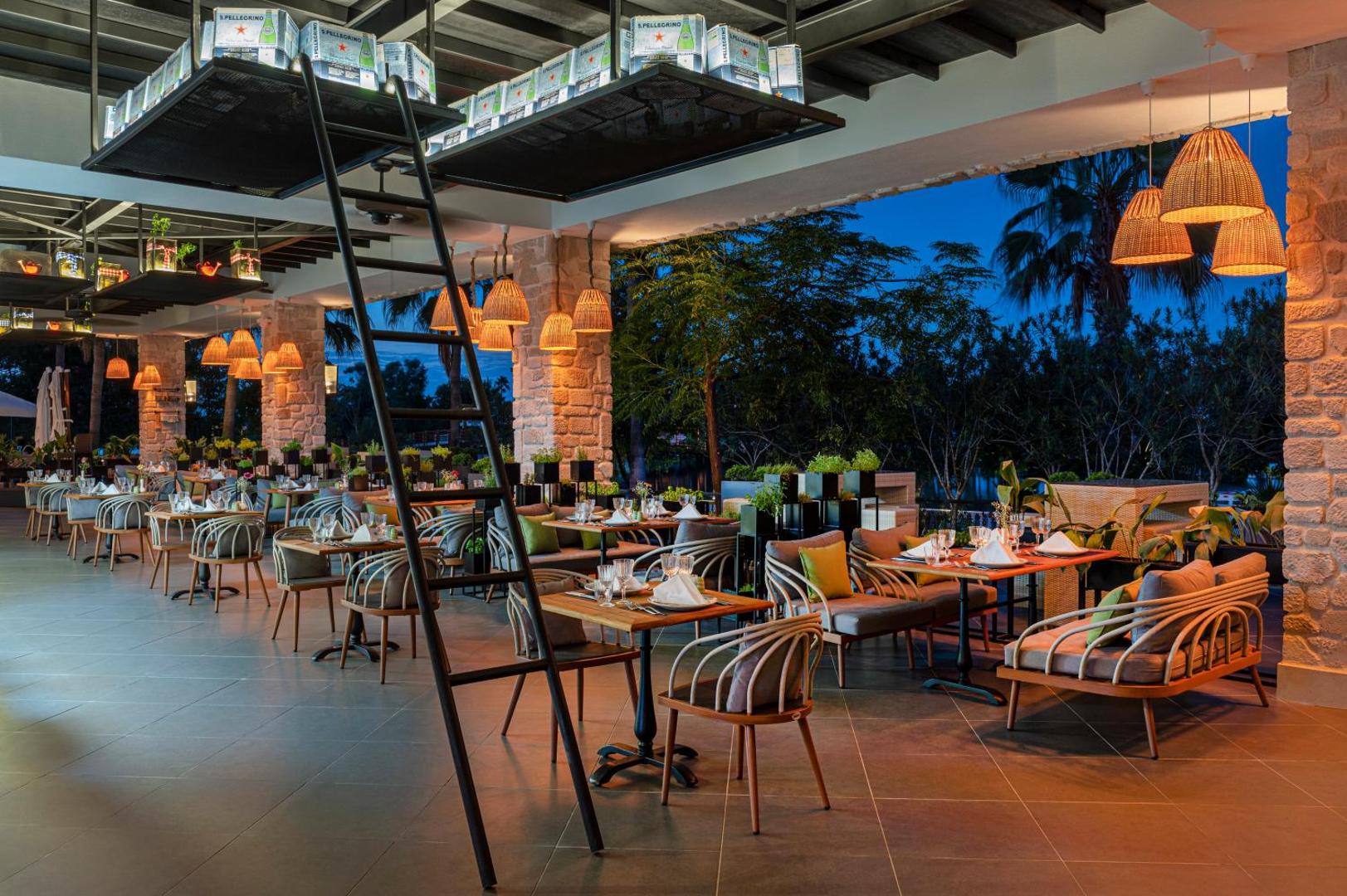 Selectum Family Resort Belek modernais restorāns ar stilīgām mēbelēm, siltu apgaismojumu un atvērtu terasi vakara stundās.