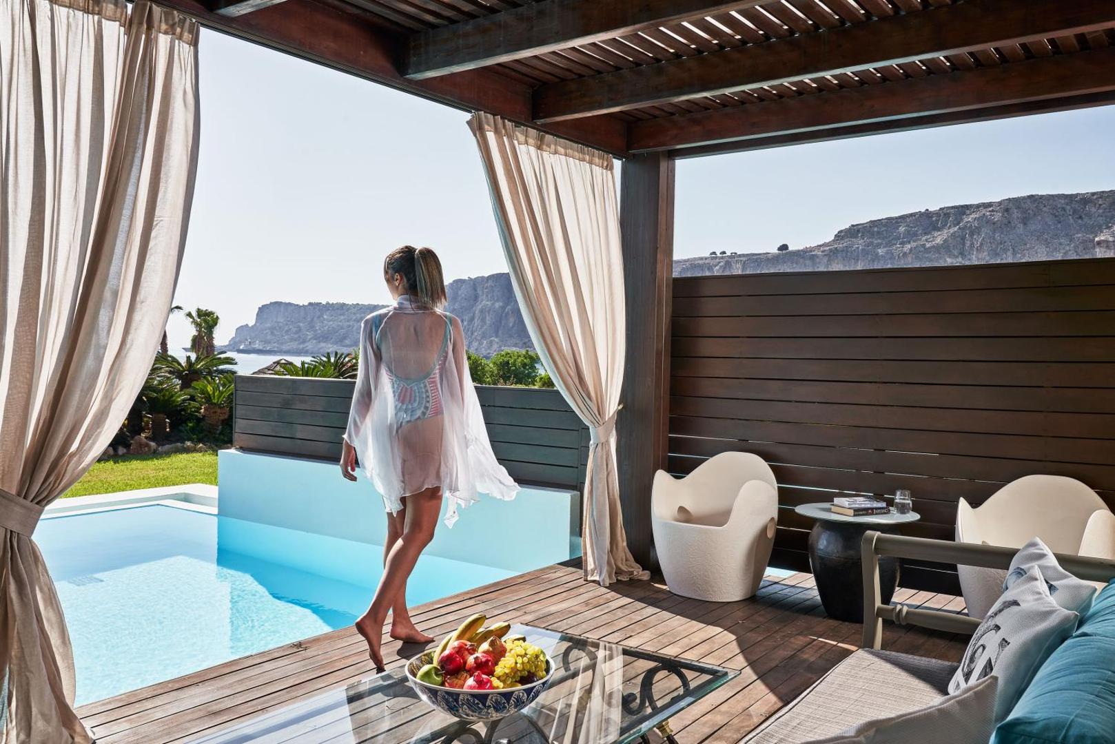 Aquagrand Exclusive Deluxe Resort numurs ar tiešu piekļuvi baseinam un privātu koka terasi ar skatu uz piekrastes klintīm