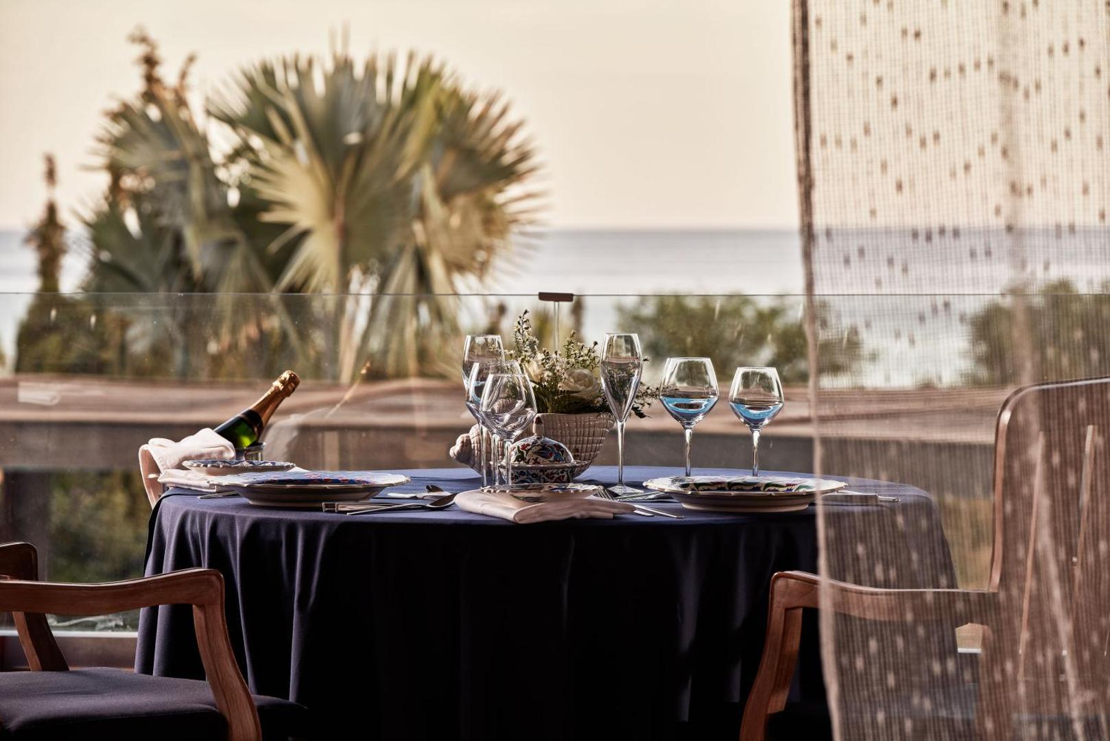 Eleganti klāts galds divām personām Aquagrand Exclusive Deluxe Resort terasē ar šampanieti un skatu uz Egejas jūru saulrietā