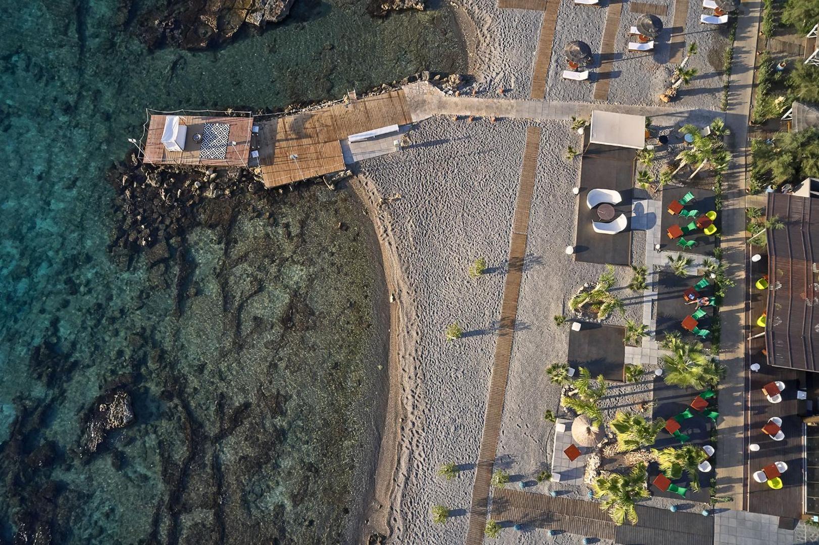 Aerofoto skats uz Aquagrand Exclusive Deluxe Resort privāto pludmali, koka laipām un atpūtas zonām pie dzidra ūdens