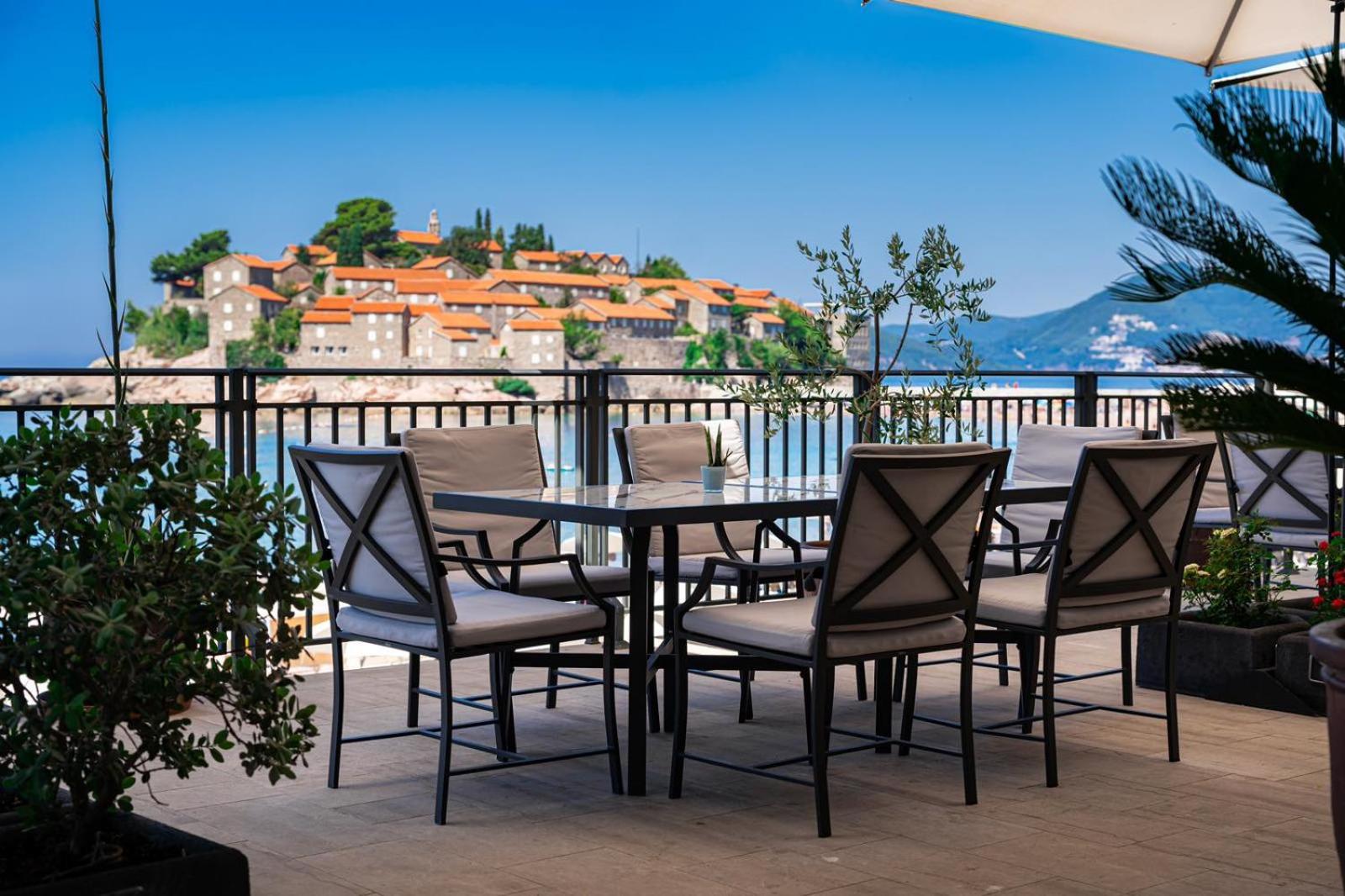 California by Aycon āra terase ar modernām mēbelēm un panorāmas skatu uz vēsturisko Sveti Stefan ciematu Melnkalnē
