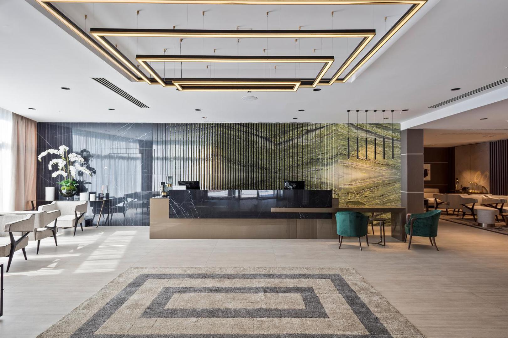 Hotel Ami Budva Petrovac modernā recepcija ar marmora apdari, dizaina gaismekļiem un plašu vestibila zonu Melnkalnes piekrastē.