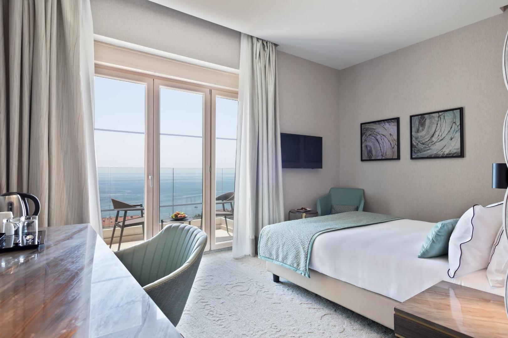 Hotel Ami Budva Petrovac numura skats no darba zonas uz balkonu, kur redzama jūra un piekrastes ainava.