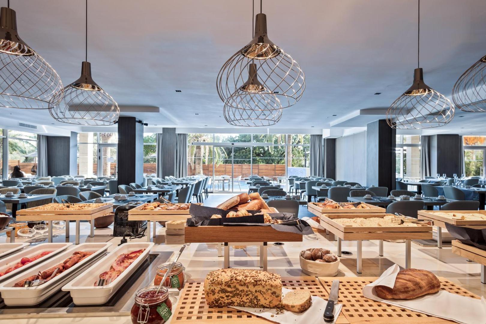 Hotel Ami Budva Petrovac brokastu bufete ar plašu maizes, smalkmaizīšu un silto ēdienu izvēli gaišā, modernā restorāna zālē Melnkalnē.