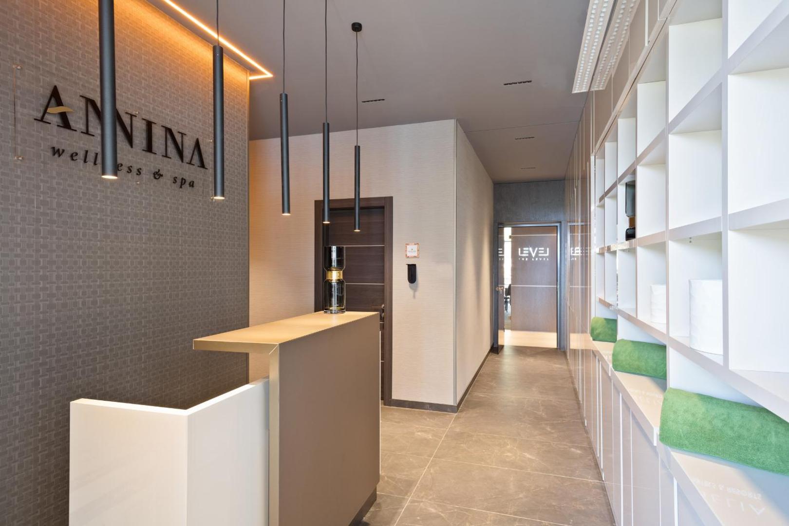 Hotel Ami Budva Petrovac Annina wellness un spa centra recepcija ar modernu apgaismojumu un gaišiem plauktiem Petrovacā