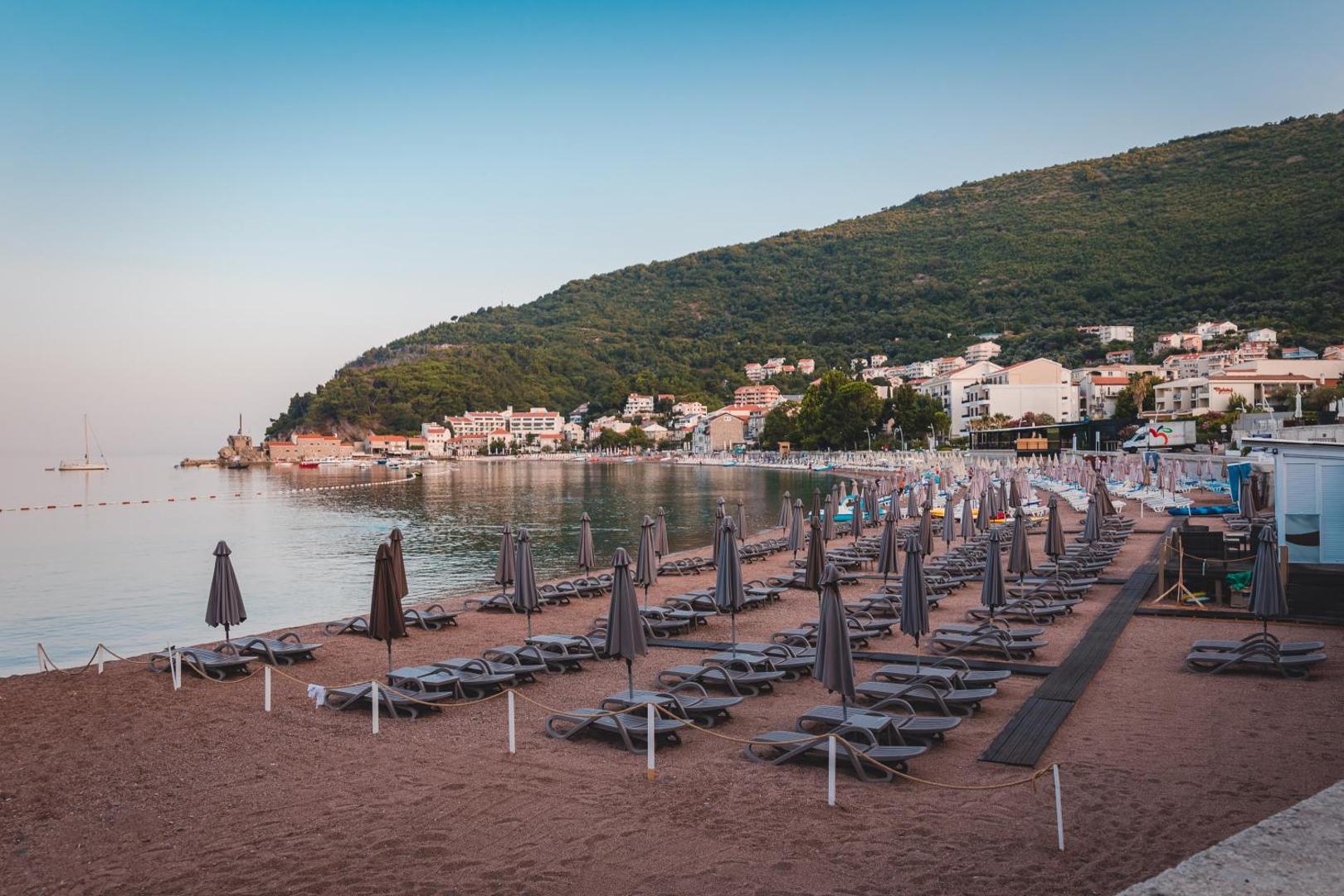 Plašs skats uz Petrovacas līci un Hotel Ami Budva Petrovac pludmali, fonā kalni un pilsētas apbūve Melnkalnes piekrastē.