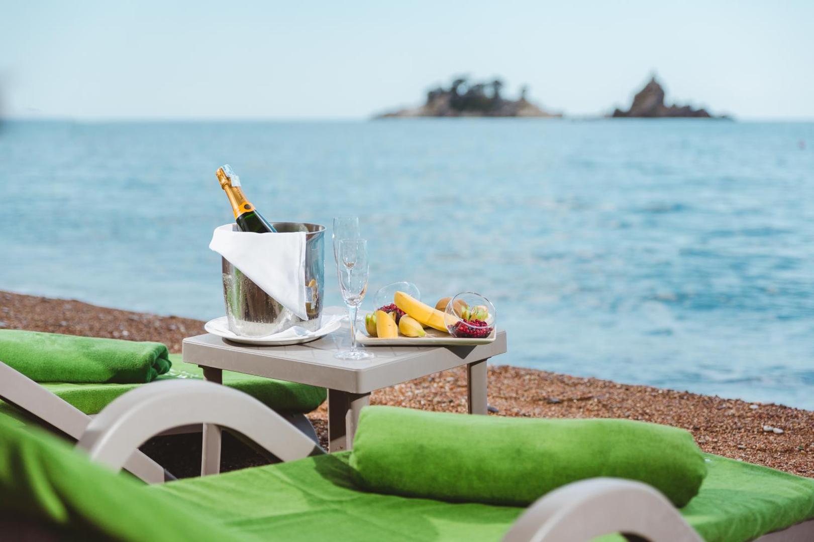 Atvēsināts dzēriens un augļu plate uz galdiņa Hotel Ami Budva Petrovac pludmalē, fonā jūra un salas Petrovacā.