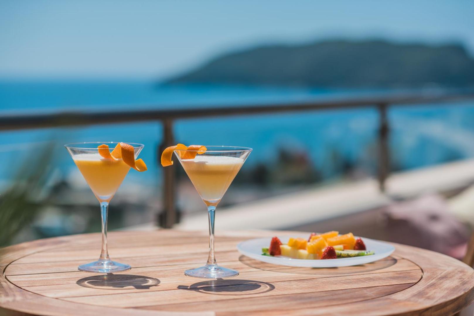 Iberostar Waves Slavija kokteiļi uz terases ar skatu uz Adrijas jūru — divas glāzes un augļu plate saulainā dienā