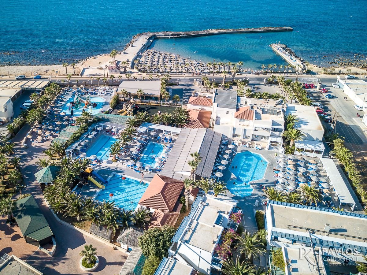 Viesnīcas komplekss pie pludmales ar peldbaseiniem un palmām, kas apņem relaksācijas zonu. Skats uz jūru un saulainu pludmali. panoramic view with beach and pools