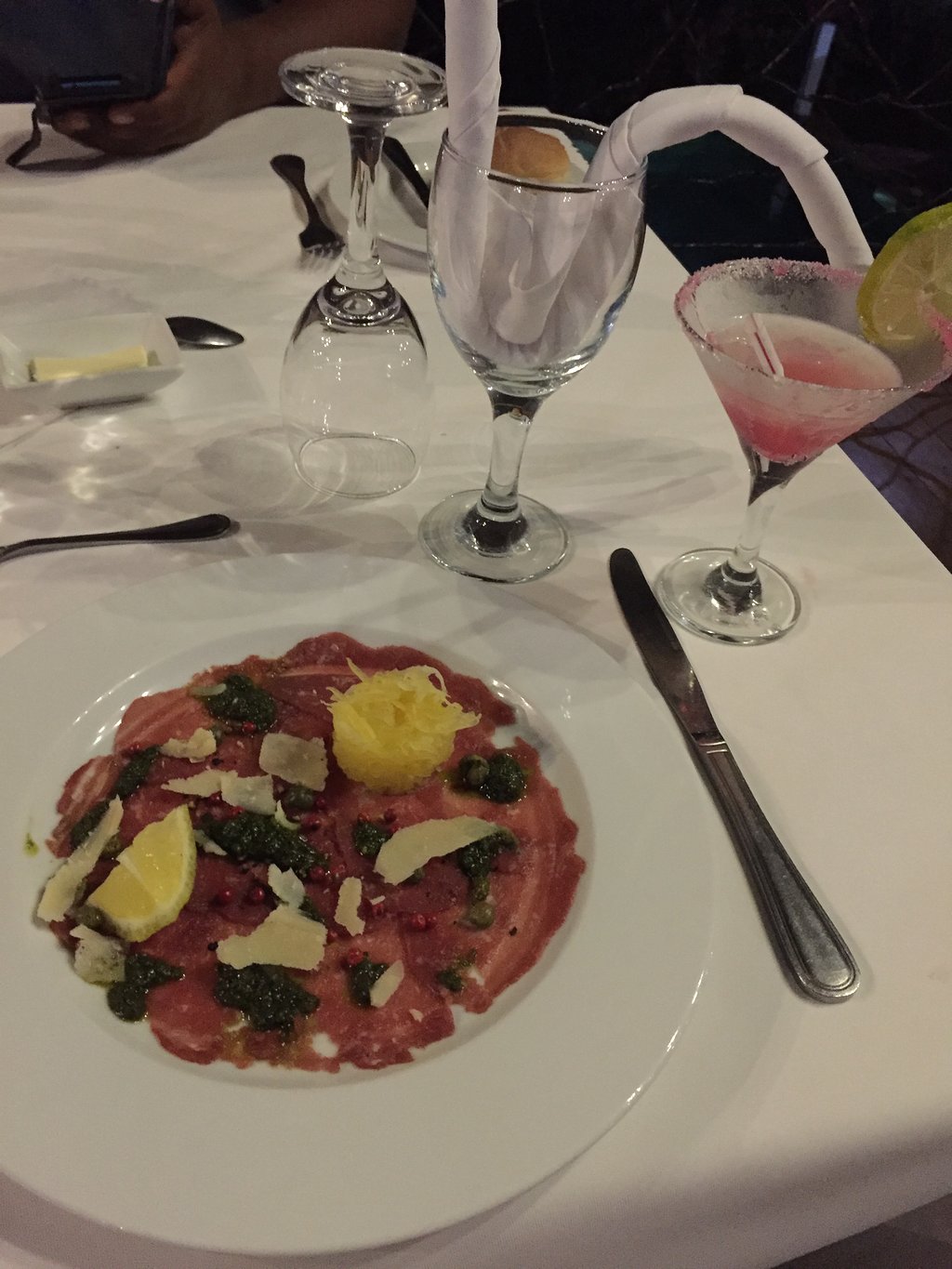 Maltas liellopa carpaccio ar pesto un kokteili uz galda Hotel Plumeria restorānā