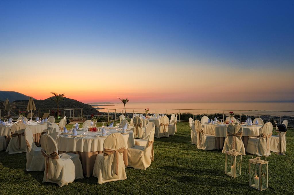 Romantiska vakariņas ārā ar galdiem, kas rotāti ar ziediem, un skaistu skatu uz horizontu saulrieta gaismā. Ideāli piemērots pasākumiem un svinībām.