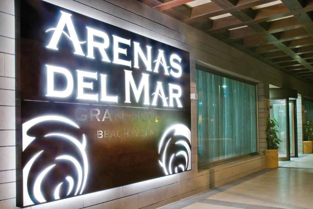 Arenas del Mar viesnīcas izkārtnes attēls ar modernu dizainu, kas ietver gaismas efektus un stilizētus ziedu elementus. Viesnīca piedāvā pludmales un spa pakalpojumus.