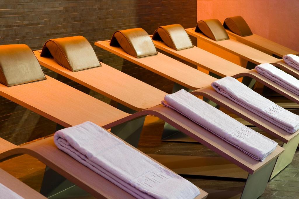 Spa atpūtas zonas gultas ar mīkstiem spilveniem un salocītiem dvieļiem, radot relaksējošu atmosfēru.