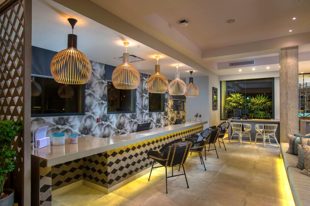 Mūsdienīgs viesnīcas reģistratūras interjers ar stilīgām lampām, dekoratīvu sienu un ērtām krēslām. Gaismas akcenti rada patīkamu atmosfēru.