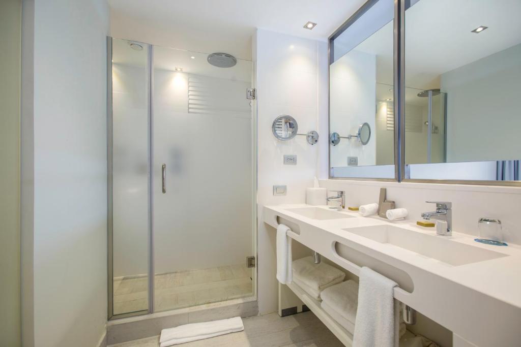 Moderns vannas istabas dizains ar stikla dušu un diviem izlietnēm, kas aprīkotas ar mūsdienīgiem santehnikas elementiem. Interjers ir gaišs un minimālistisks, radot relaksējošu atmosfēru.