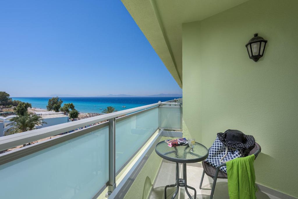 Balcony with a stunning sea view, featuring a small table and a chair adorned with a hat and beach towel, perfect for a relaxing getaway.