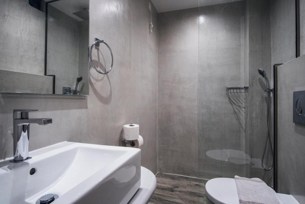 Mūsdienīgs vannas istabas interjers ar pelēkām sienām, stikla dušu un minimālistisku izlietni. Ideāls dizains mūsdienīgai dzīves telpai.