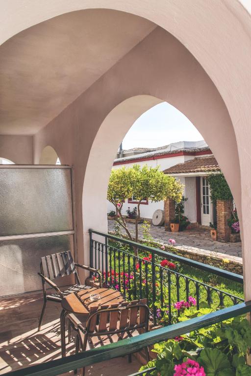 Balkona skats ar koka krēsliem un ziediem, kas rotā dārzu, radot mierīgu un mājīgu atmosfēru.