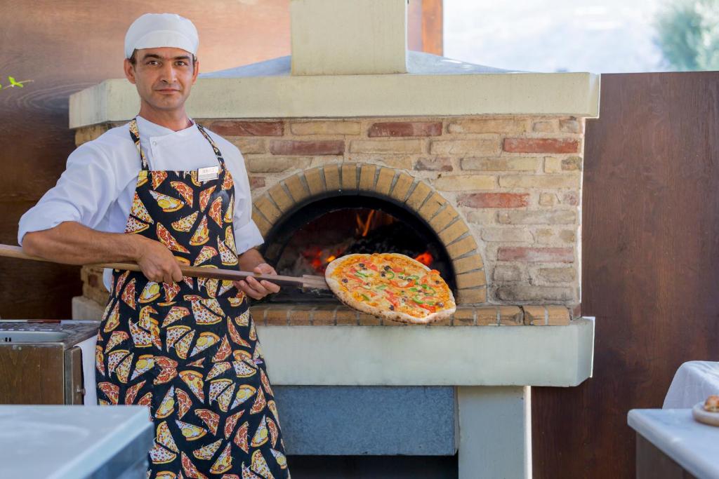 Šefpavārs pie Dessole Malia Beach izņem picas no koka krāsns.