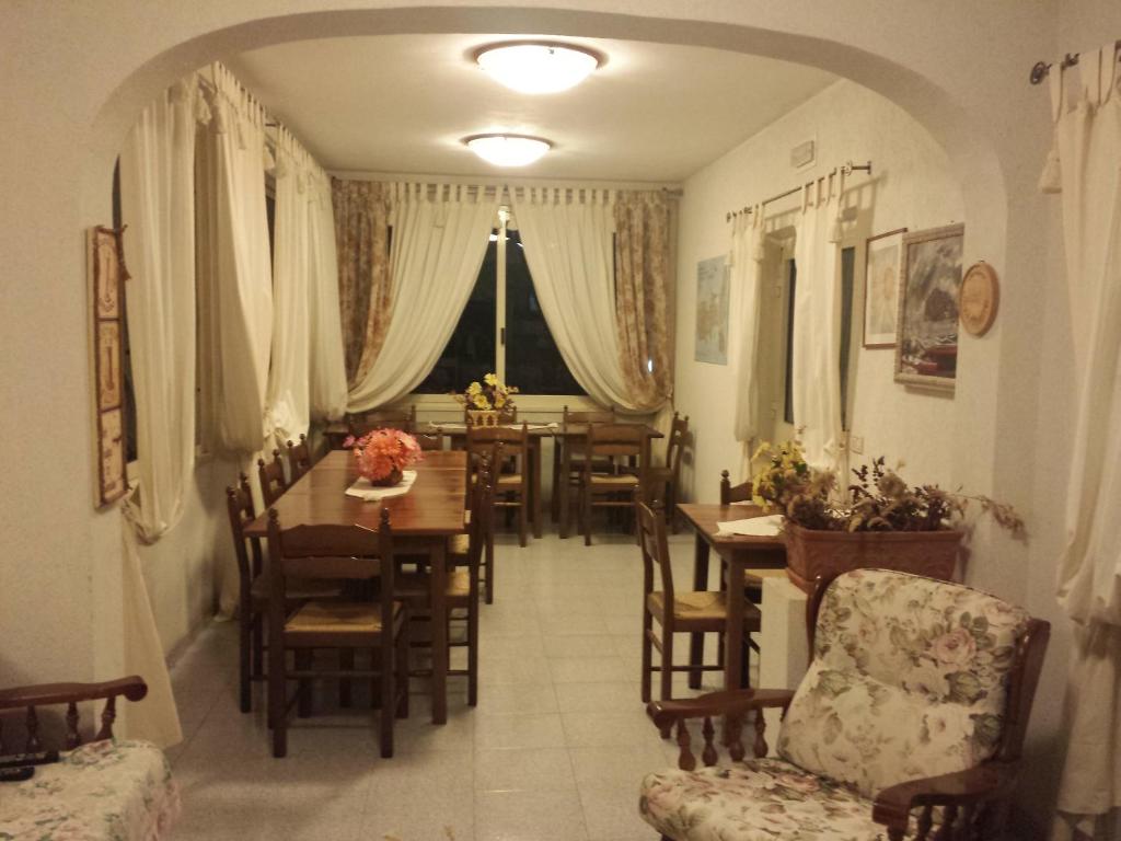 Mājas interjera skats ar ēdamgaldu un krēsliem, apgaismojumu un logiem, ko rotā aizkari. Siltas krāsas un mājīga atmosfēra rada patīkamu vidi.