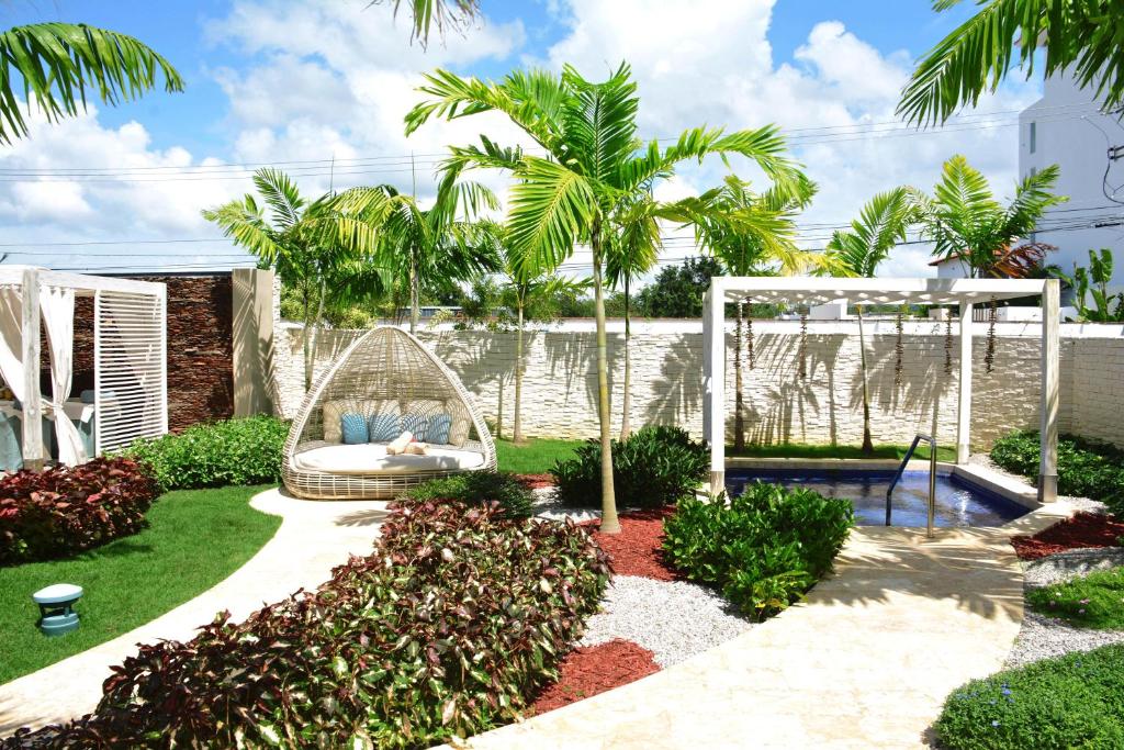 Skaists dārza ainava ar šūpuļkrēslu, palmām un nelielu baseinu, kurā ir zaļa zāle un krāsaini krūmi. Ideāla vieta atpūtai un relaksācijai.