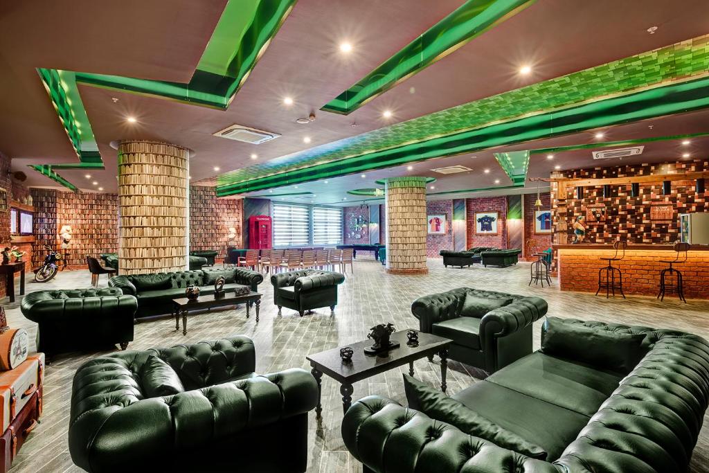 Mūsdienīga viesnīca Magic Life Jacaranda stila atpūtas zona ar zaļiem dīvāniem.