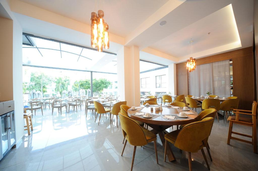 Mūsdienīgs restorāns ar dzeltenām krēslām un plašiem logiem Atrium Ambiance Hotel.