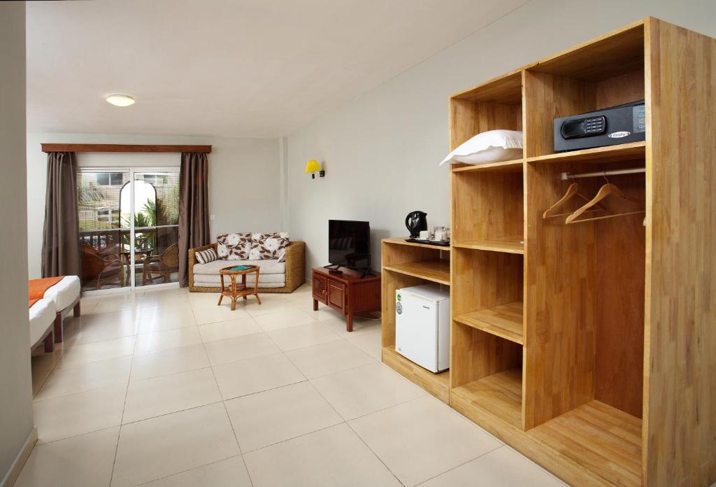 Mūsdienīga viesnīcas istaba ar dzīvojamo zonu, dīvānu un galdiņu, kā arī skapīti un ledusskapi. Labi apgaismota telpa ar balkonu un skatu uz dārzu.