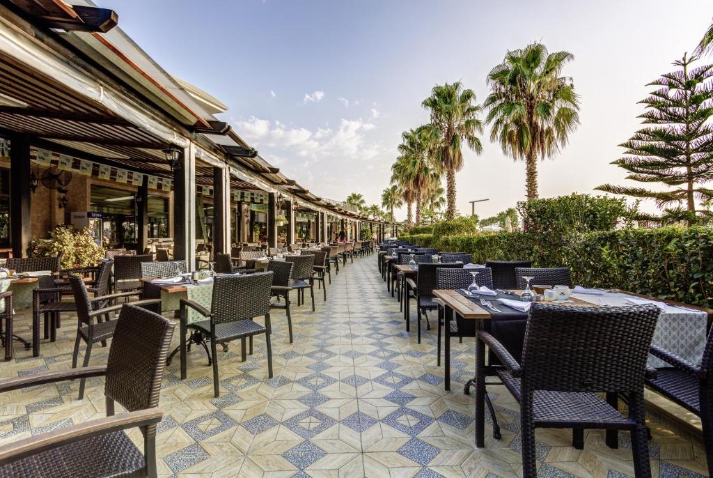 Āra restorāns pie viesnīcas Magic Life Jacaranda ar palmām un galdiem.