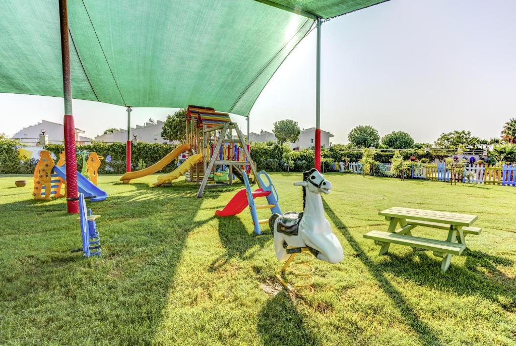 Bērnu rotaļu laukums pie viesnīcas Magic Life Jacaranda ar slīdni un šūpolēm.
