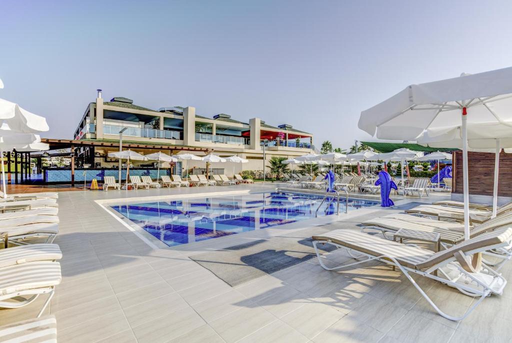 Peldbaseins pie Magic Life Jacaranda ar sauļošanās krēsliem