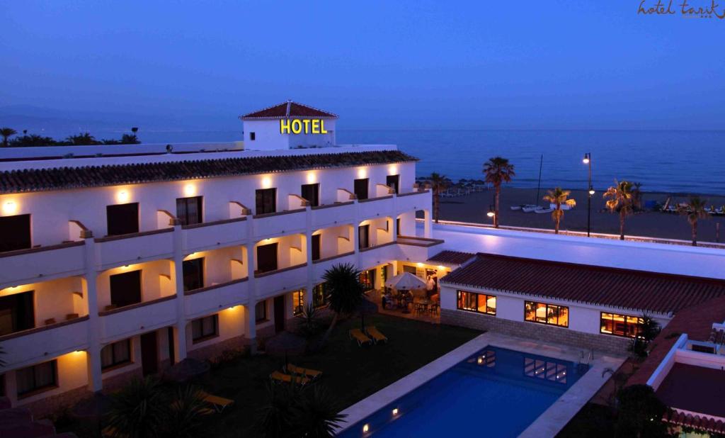 Viesnīca pie pludmales, apgaismota vakara stundās, ar baseinu un palmām apkārt. Ideāla vieta atpūtai un relaksācijai.