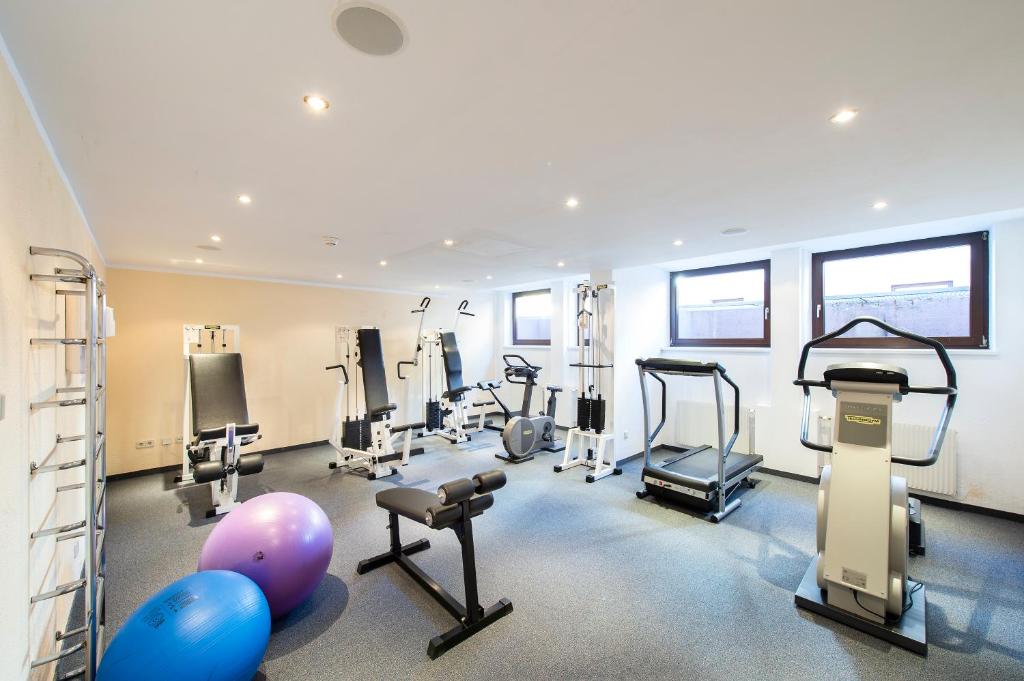 Mūsdienīgs trenažieru zāles interjers ar dažādām trenažieru iekārtām, jogas bumbām un logiem, kas nodrošina dabisko apgaismojumu.