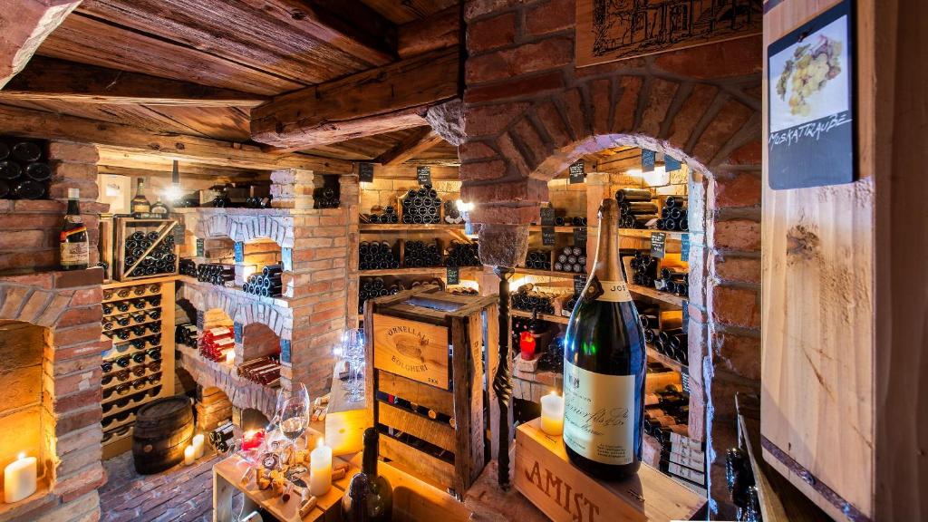 Vīna pagrabs ar ķieģeļu sienām, kurā glabājas dažādas vīna pudeles un citi dzērieni, radot siltu un viesmīlīgu atmosfēru. Gaisma un sveces piešķir noskaņu šai īpašajai vietai.