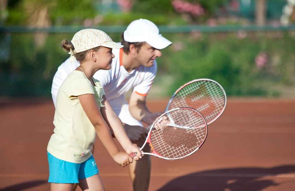 Bērns un pieaugušais spēlē tenisu Ali Bey Club