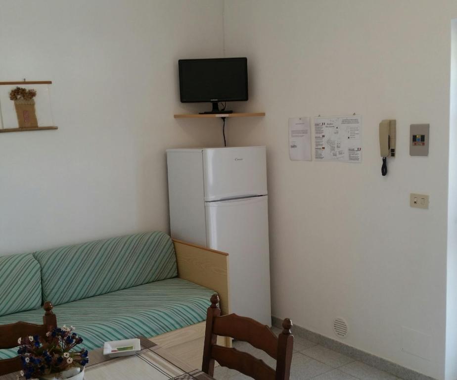 Mūsdienīgs viesistabas stūris ar dīvānu, ledusskapi un televizoru. Sienā piestiprinātas instrukcijas un telefons.