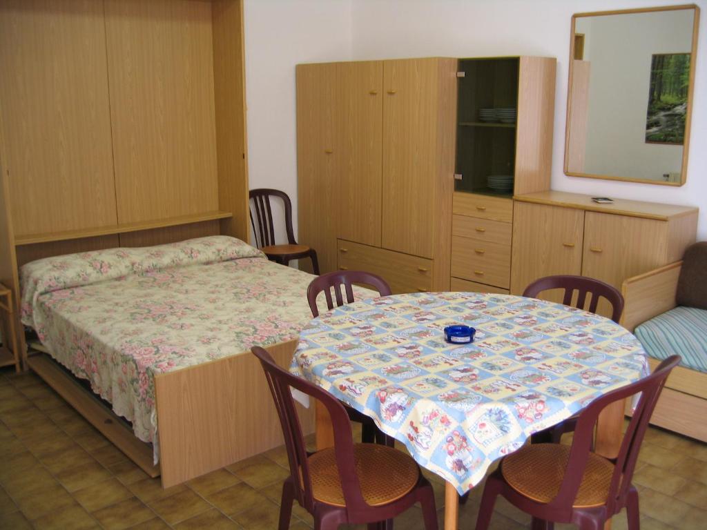 Kompakts studio dzīvoklis ar gultu, ēdamgaldu un koka mēbelēm, kas nodrošina komfortu un funkcionalitāti. Telpa aprīkota ar spoguli un skapjiem, radot mājīgu atmosfēru.