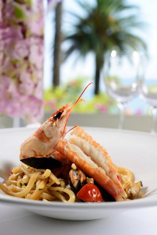 Gatavošana ar jūras veltēm un makaronu šķīvis, dekorēts ar garnelēm un dārzeņiem, ar ainavu fonā.