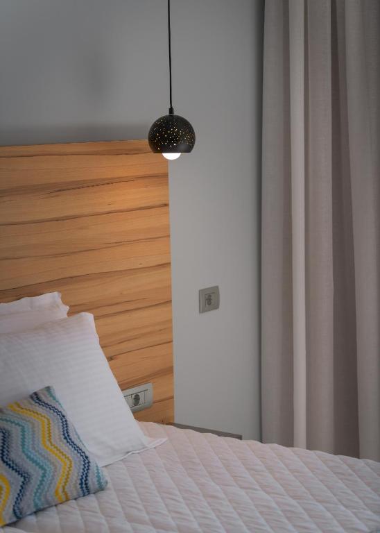 Mūsdienīgs guļamistabas interjers ar koka gultas galvu, stilīgu piekaramo gaismu un mīkstām spilveniem. Gaismas un krāsu harmonija rada relaksējošu atmosfēru.